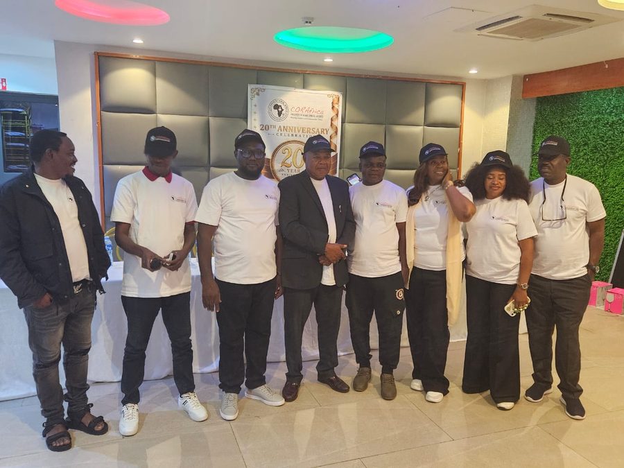 Eight guests in CORAfrica T-shirts and caps in front of the anniversary banner