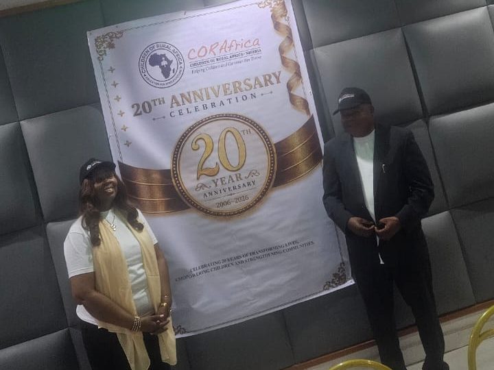 A woman and a man on either side of the twentieth-anniversary banner