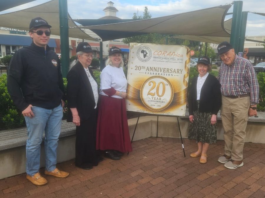 Six supporters in CORAfrica caps on either side of the twentieth-anniversary banner