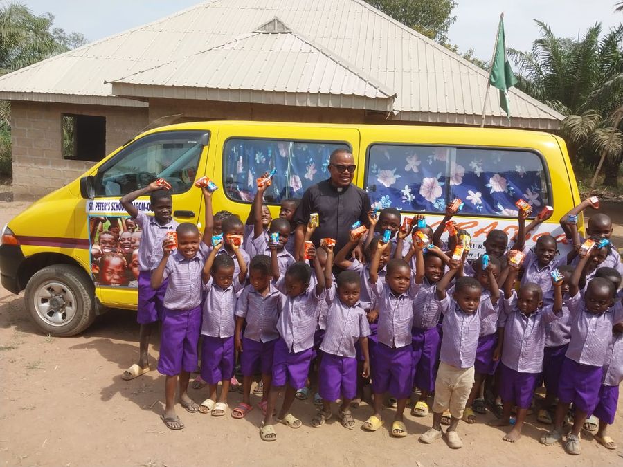 Pupils in school uniform beside a CORAfrica school bus
