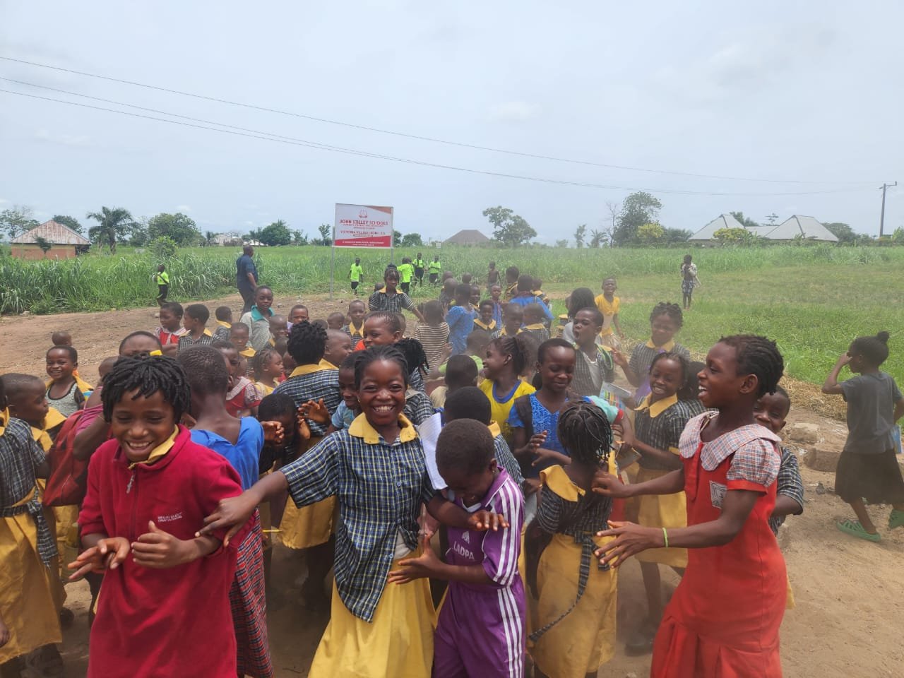 Pupils of the Victoria Schools, Ikom, laughing and playing in the schoolyard, the school sign behind them